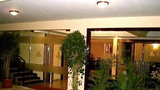 A lobby with a tiled floor, potted plants, a staircase, and a glass door leading inside. - Stamford Residency (Bengaluru)
