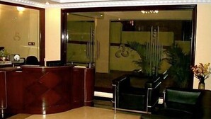 A reception area with a marble reception desk, a glass partition, and a seating area with a chair and a small table. - Stamford Residency (Bengaluru)