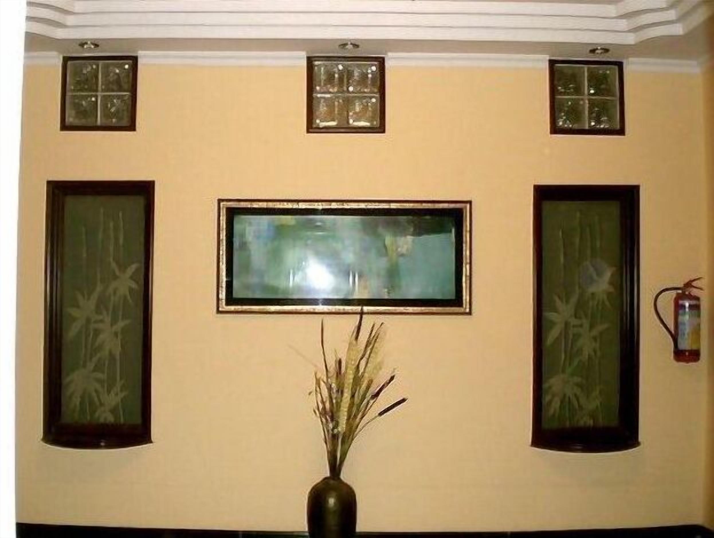 Una pared con tres cuadros enmarcados y un florero con plantas secas.