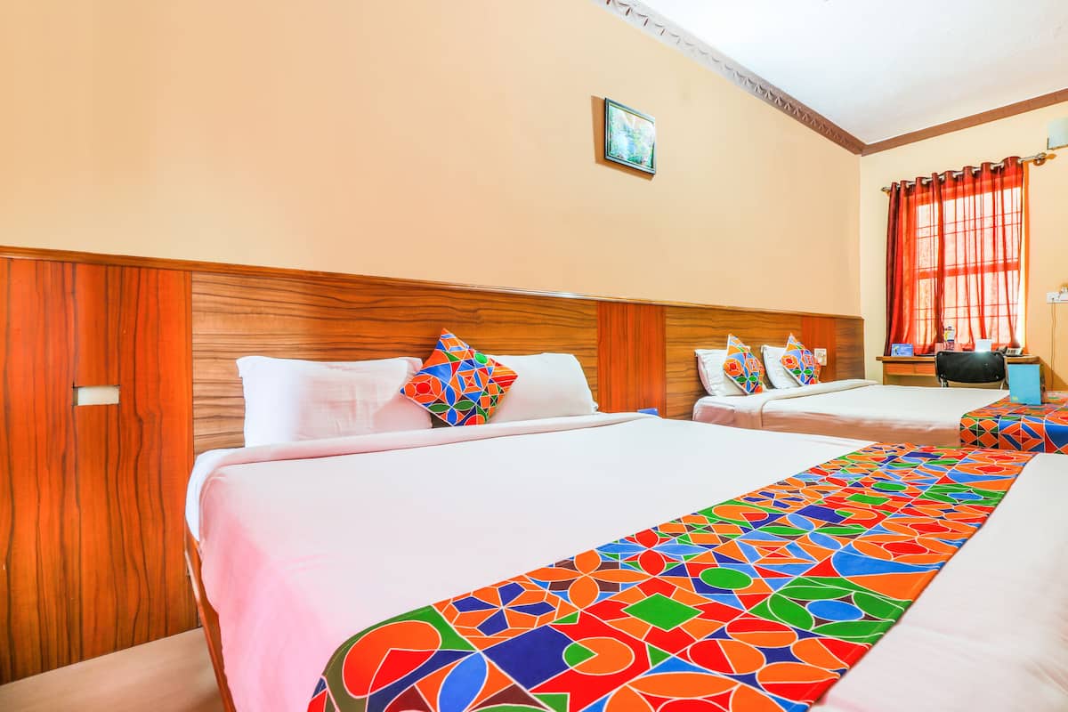 A hotel room with two beds, wooden headboards, and a colorful geometric-patterned runner.