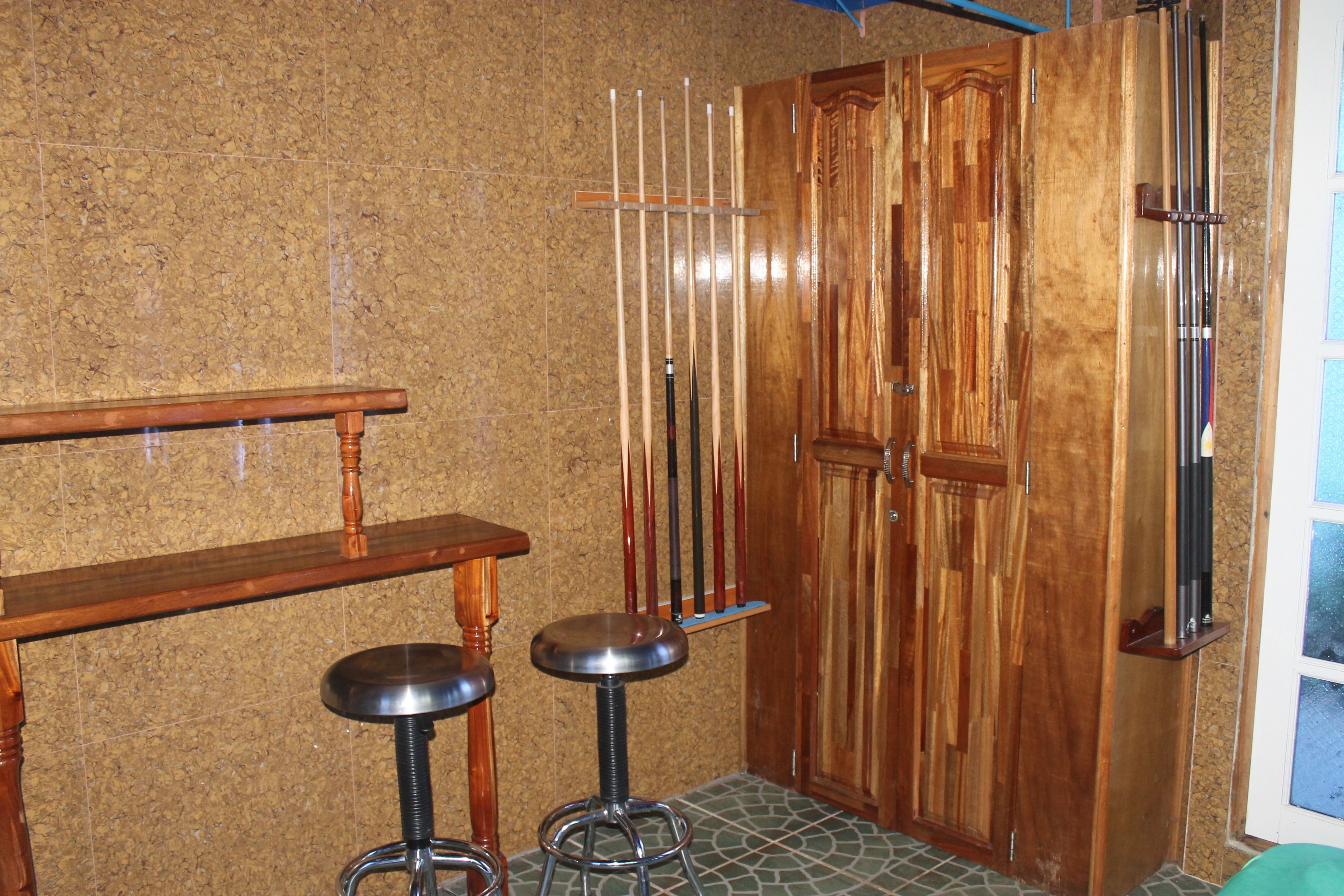 A room with a wooden bench, two stools, a door, and a window.
