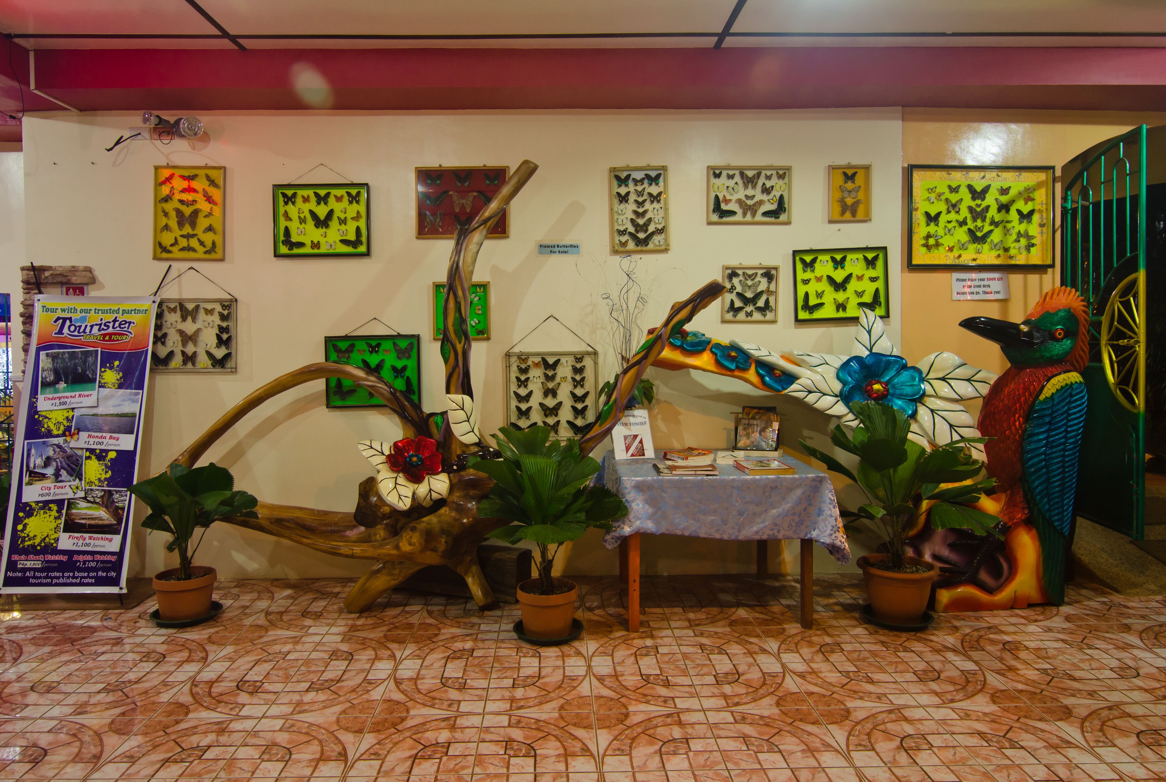 A room with a tiled floor, a table with a blue tablecloth, and several potted plants.