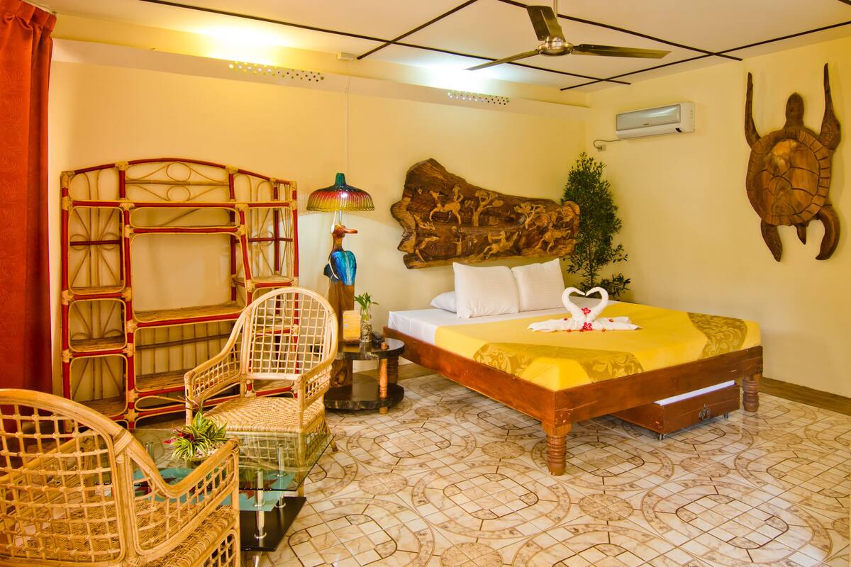 A room with a bed, a ceiling fan, a wall-mounted air conditioner, and a decorative turtle sculpture.