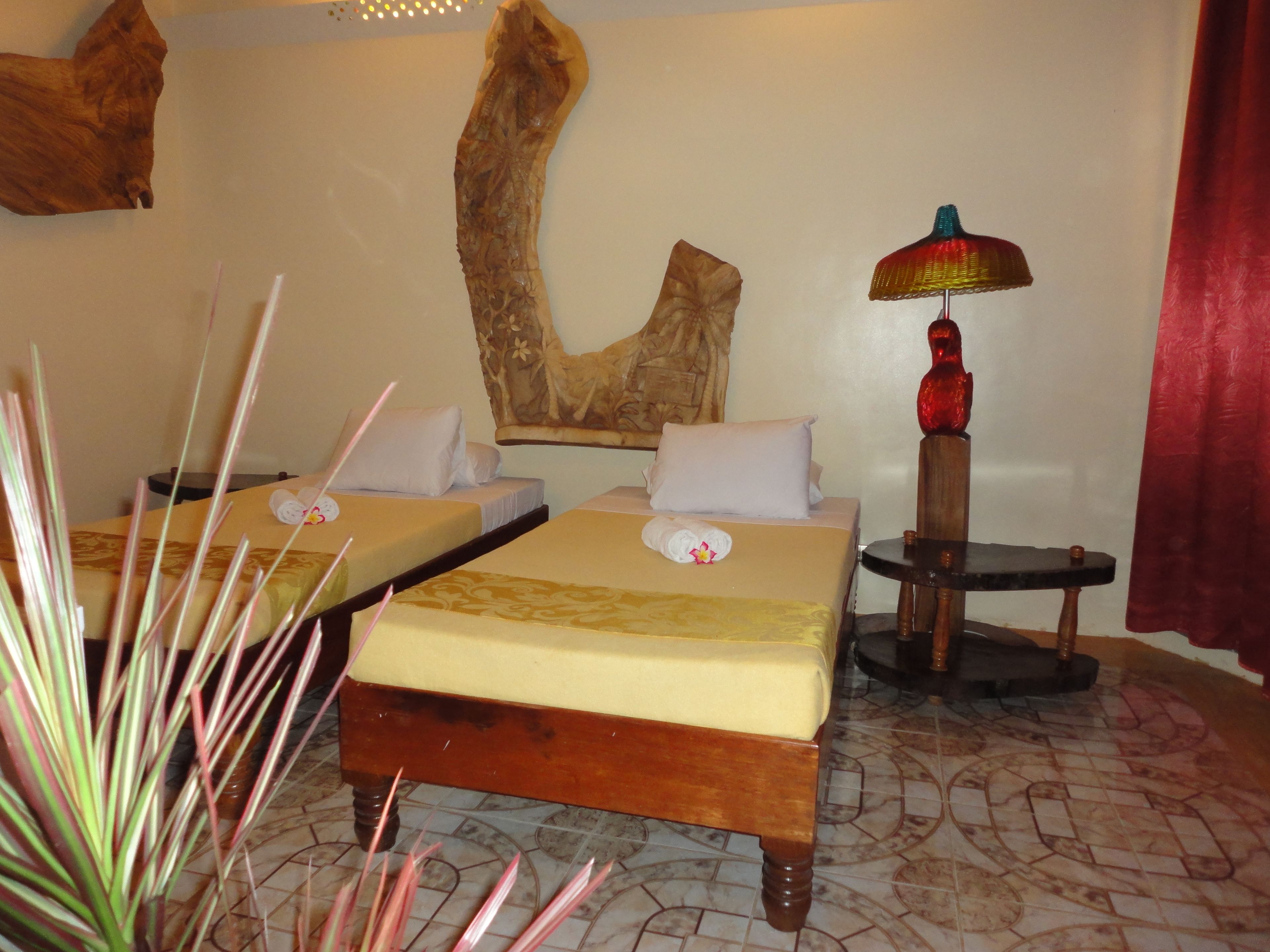Une chambre d’hôtel avec deux lits, une tête de lit en bois, une lampe rouge et une grande œuvre d’art murale.