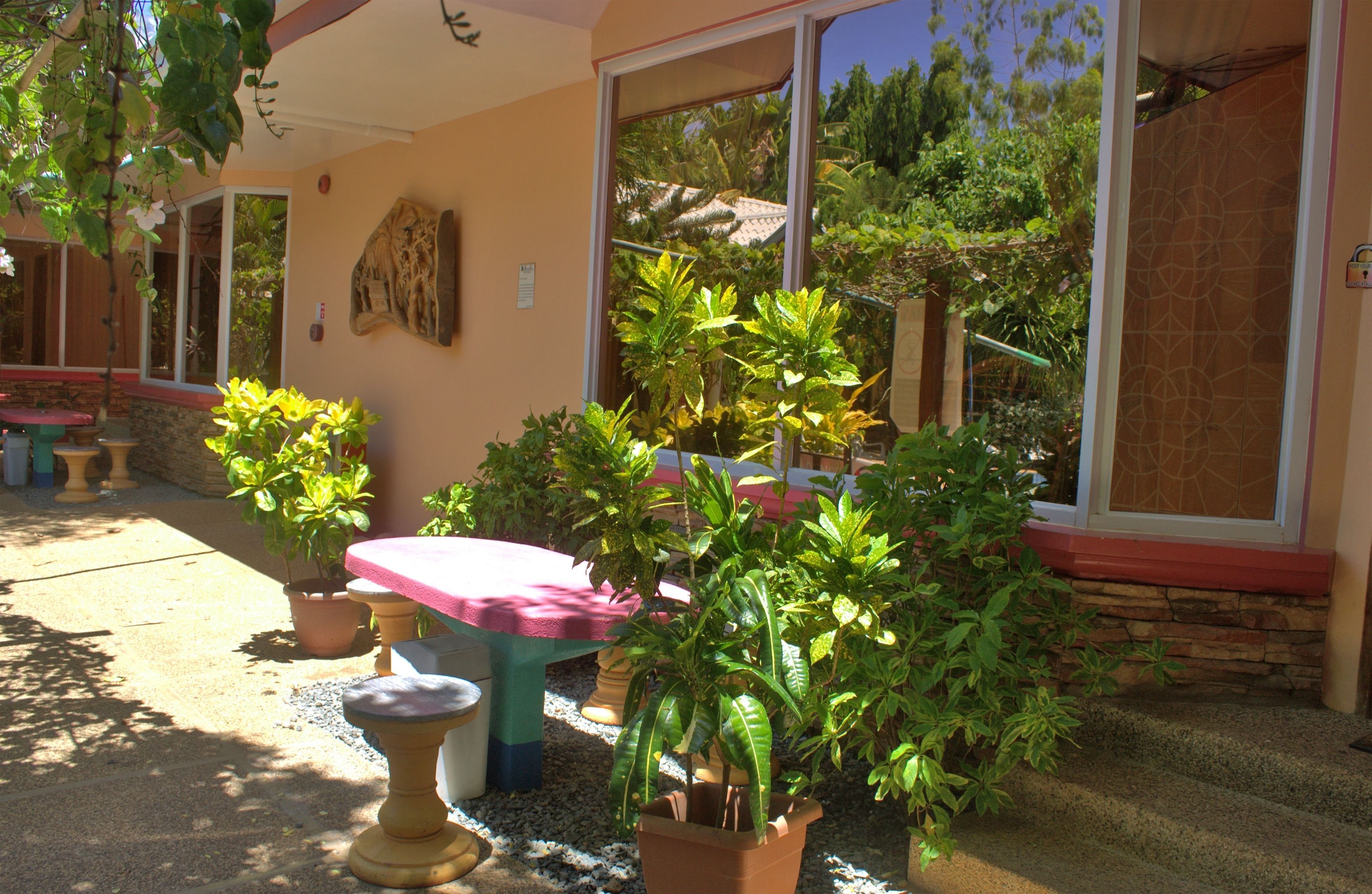 A patio area with a table and chairs, surrounded by potted plants and a stone wall.