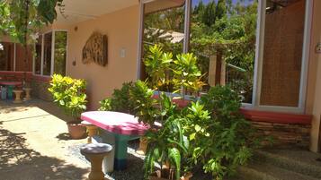 A patio area with a table and chairs, surrounded by potted plants and a stone wall.