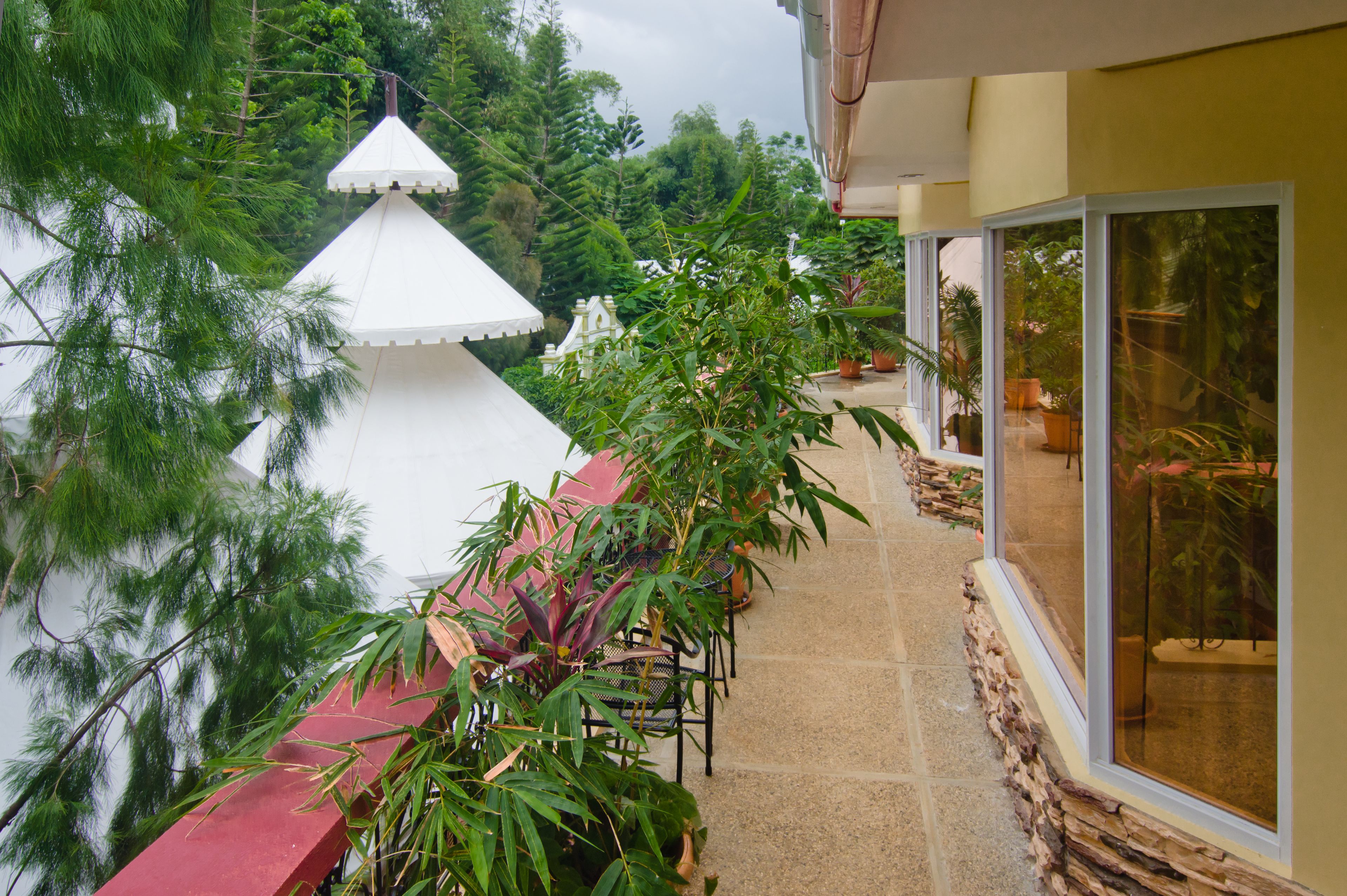 A balcony with a red railing, potted plants, and a white gazebo.