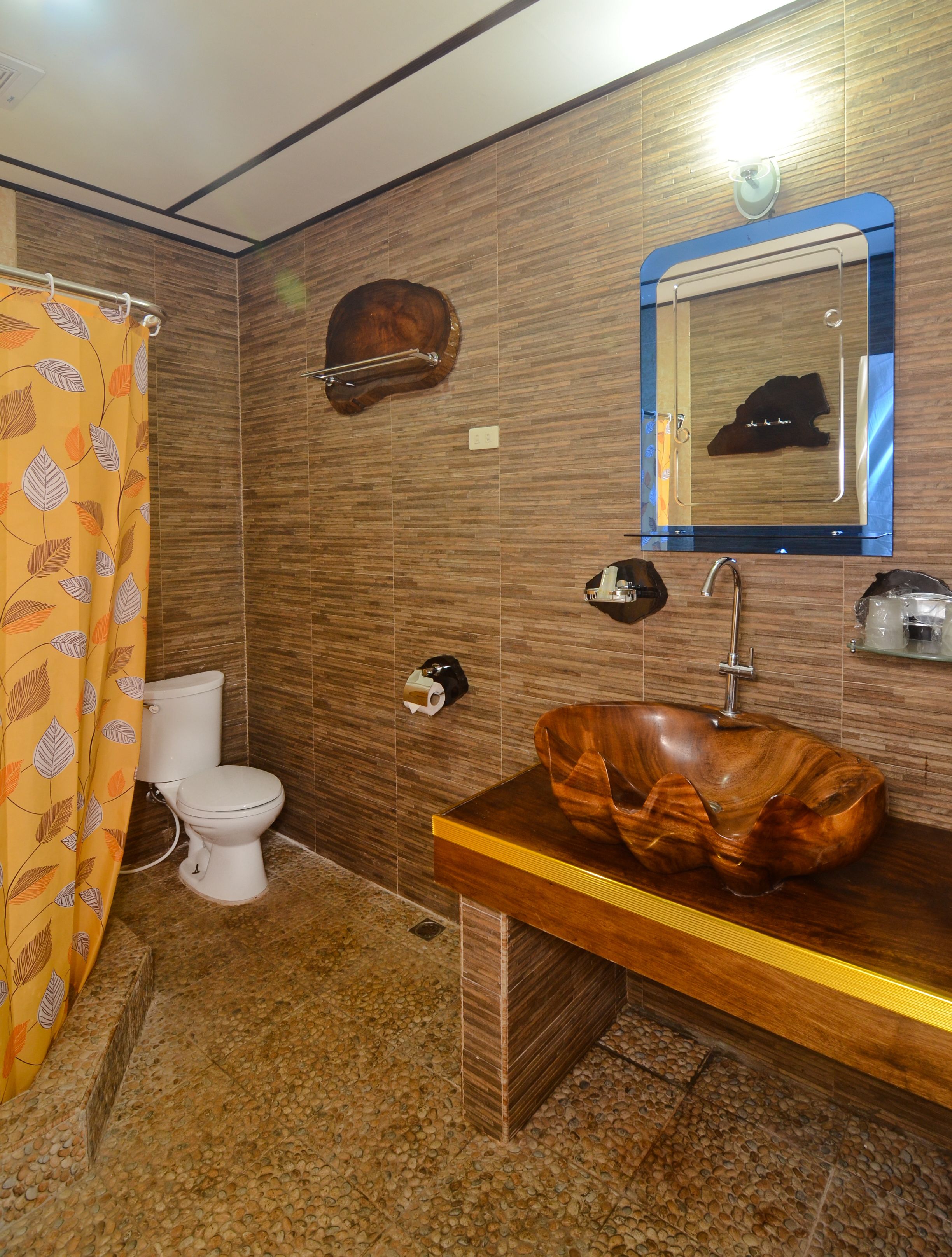 A bathroom with a wooden vanity, a sink, a mirror, and a toilet.