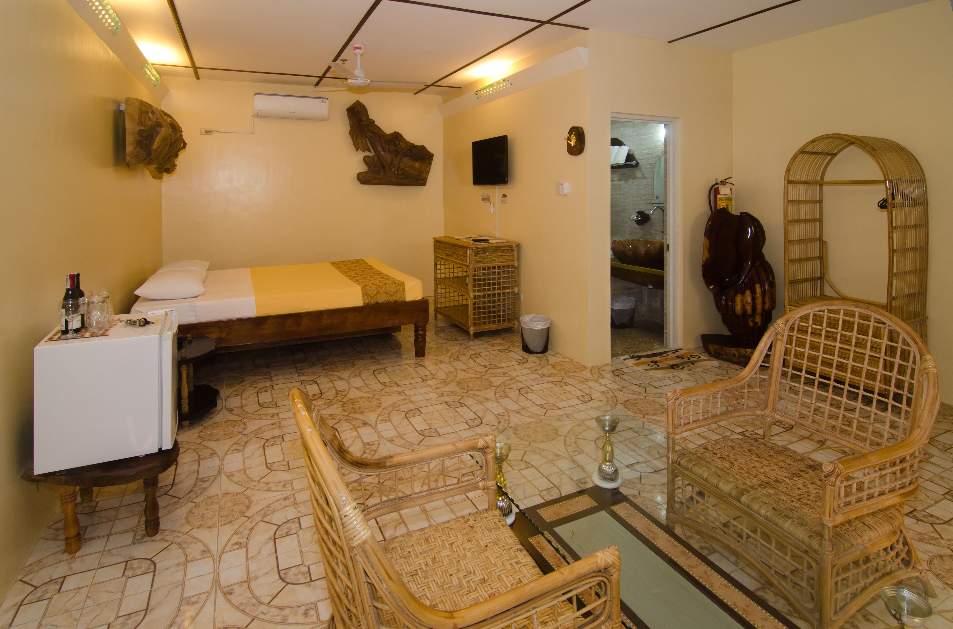 Una habitación con una cama, una mesita, una silla, un televisor y un espejo.