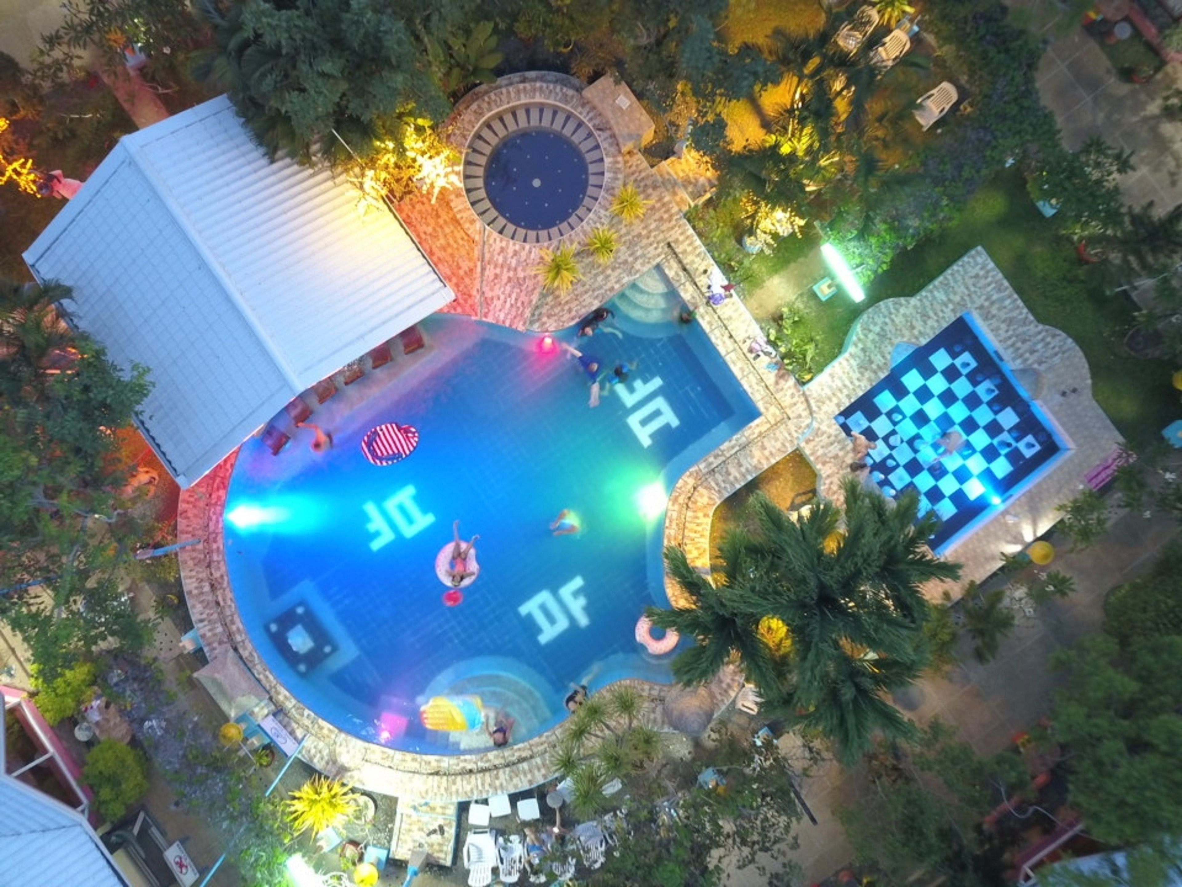 An aerial view of a resort with a large pool, a separate pool area, and a checkered lounge area.
