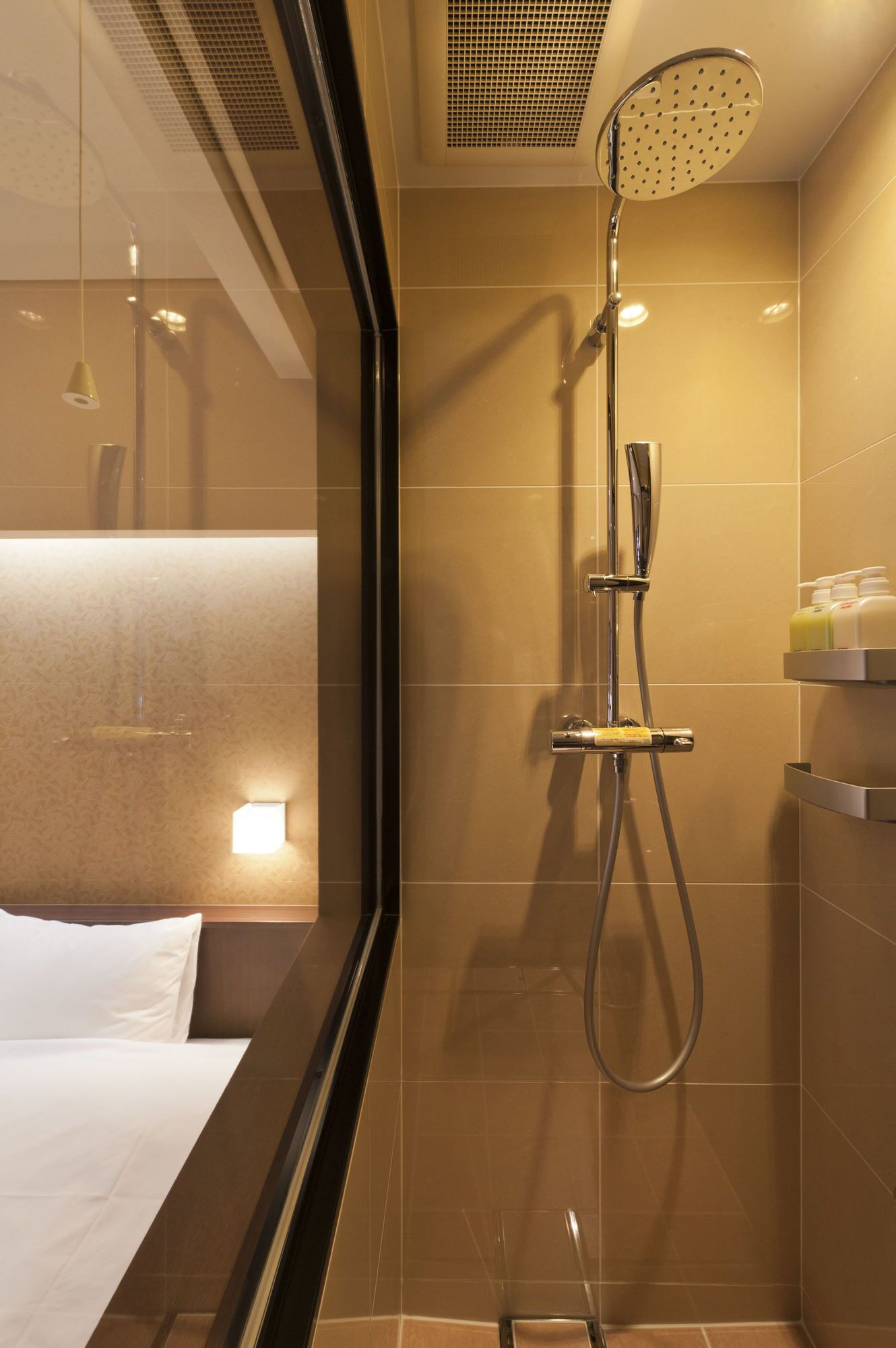 A modern bathroom with a shower, a bed, and a bedside table.