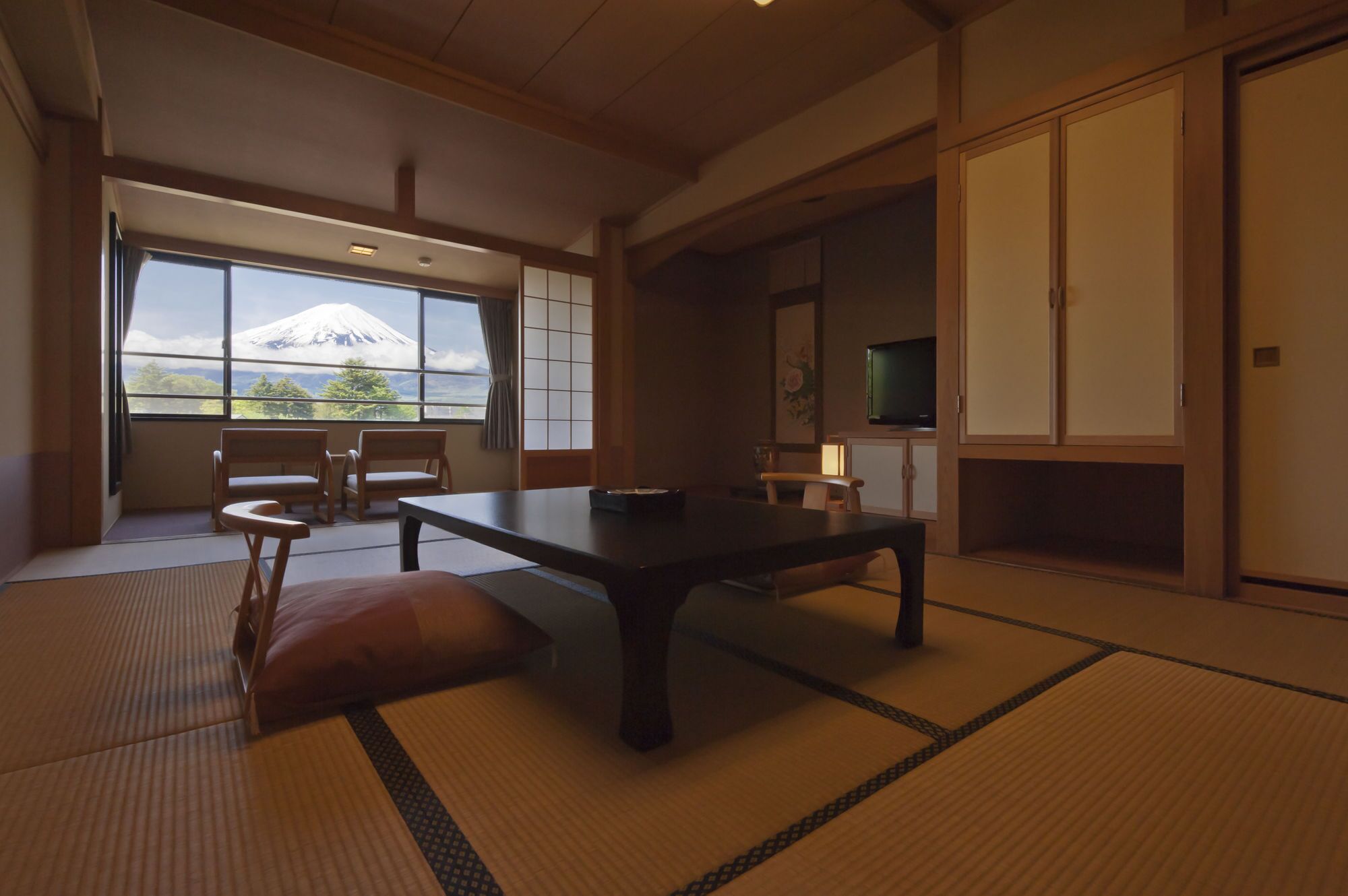 Ein traditioneller japanischer Raum mit Tatami-Böden, einem niedrigen Tisch und Blick auf den Fuji durch ein großes Fenster.