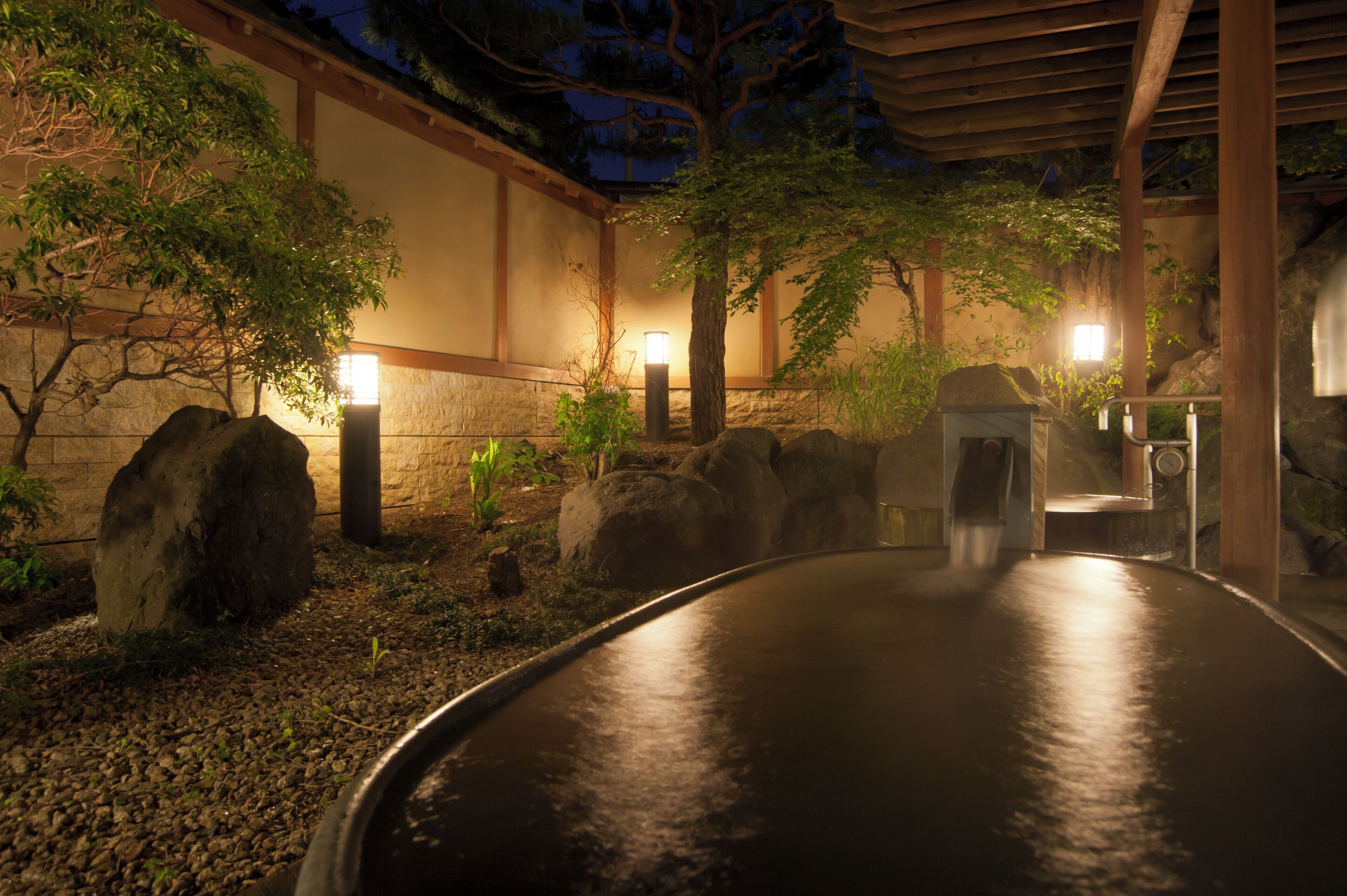 A traditional Japanese garden with a stone path, lanterns, and a wooden structure.