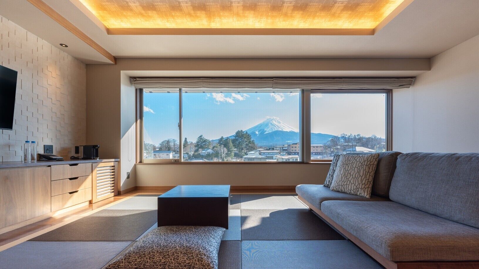 A modern living room with a sofa, a coffee table, and a TV on a wall.
