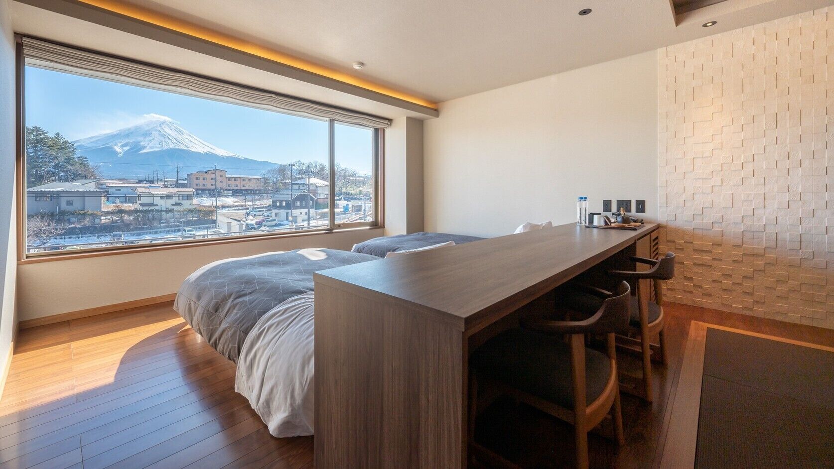 A bedroom with a bed, a desk, and a view of a mountain.