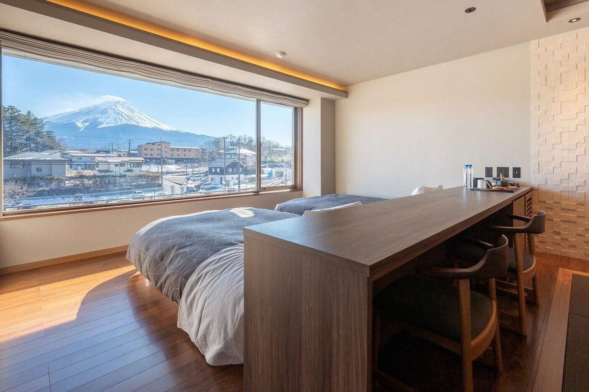 A bedroom with a bed, a desk, and a view of a mountain.