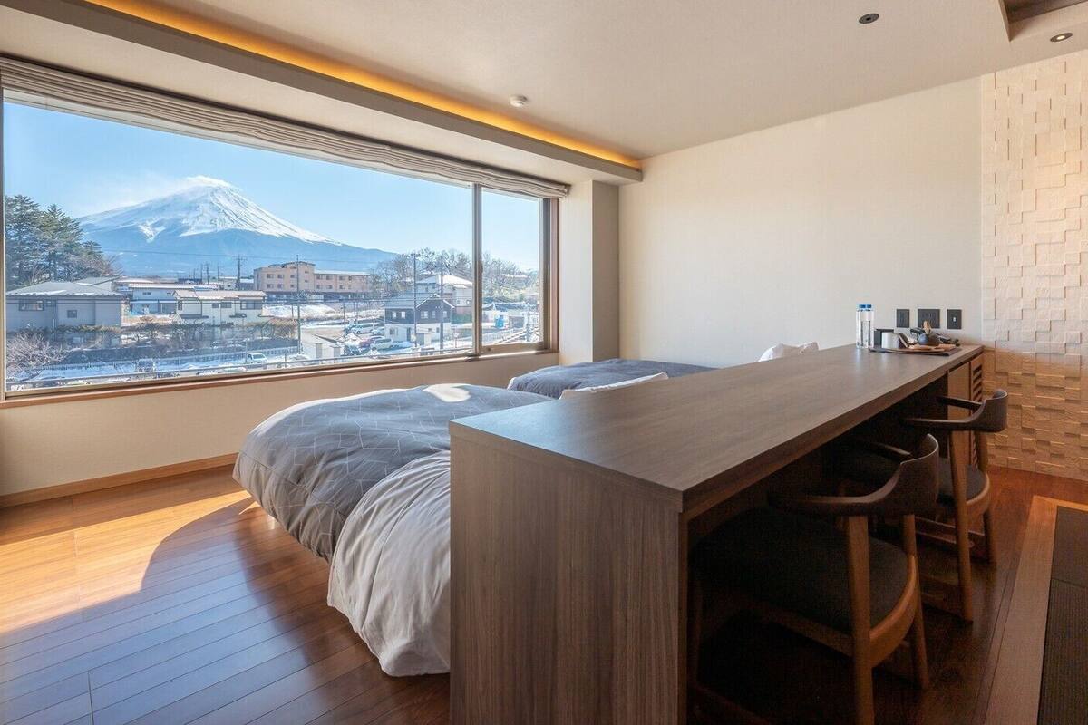 Une chambre avec un lit, un bureau et une vue sur une montagne.
