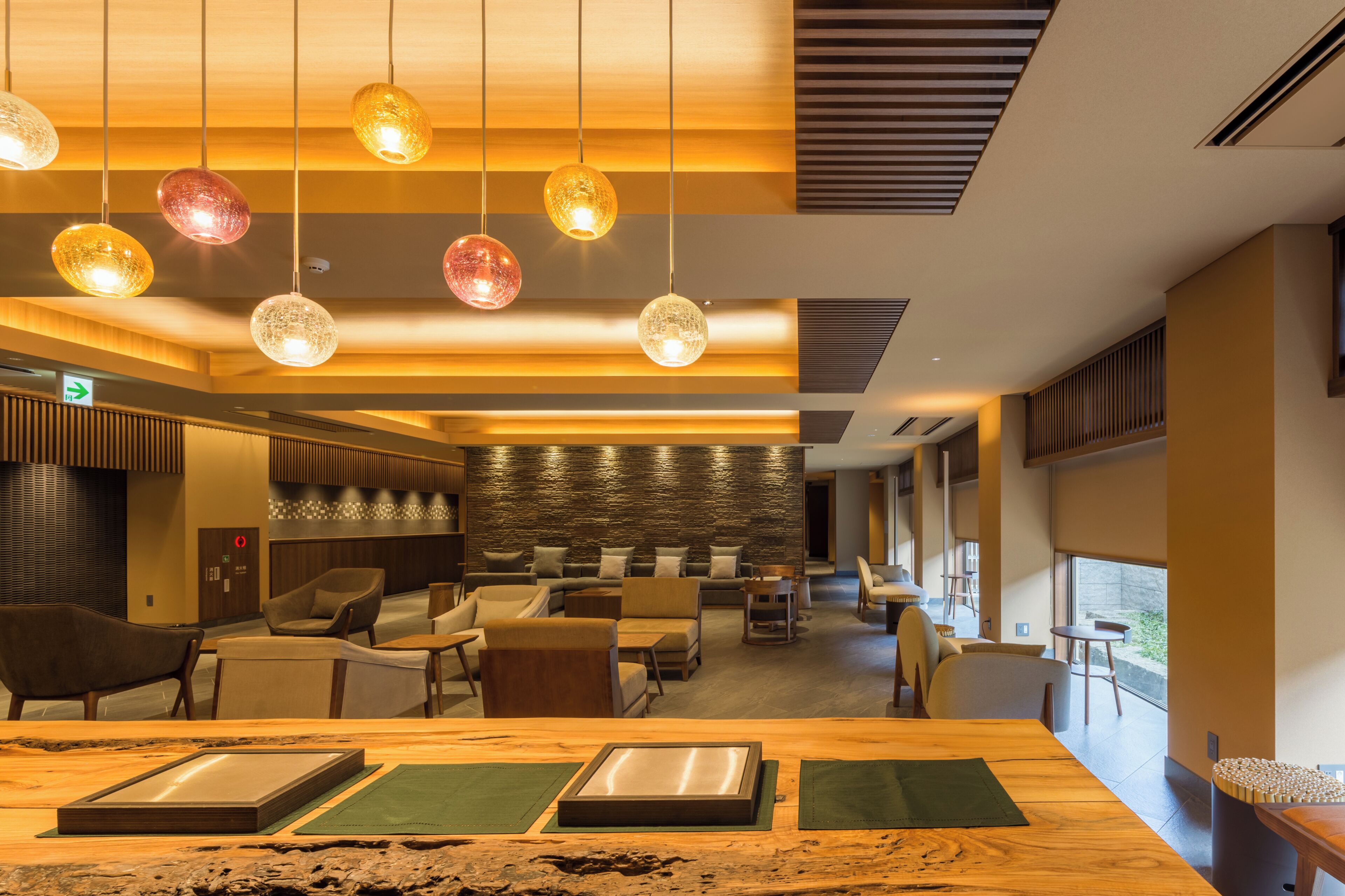 A modern hotel lobby with seating, a reception desk, and a view of the outdoors.