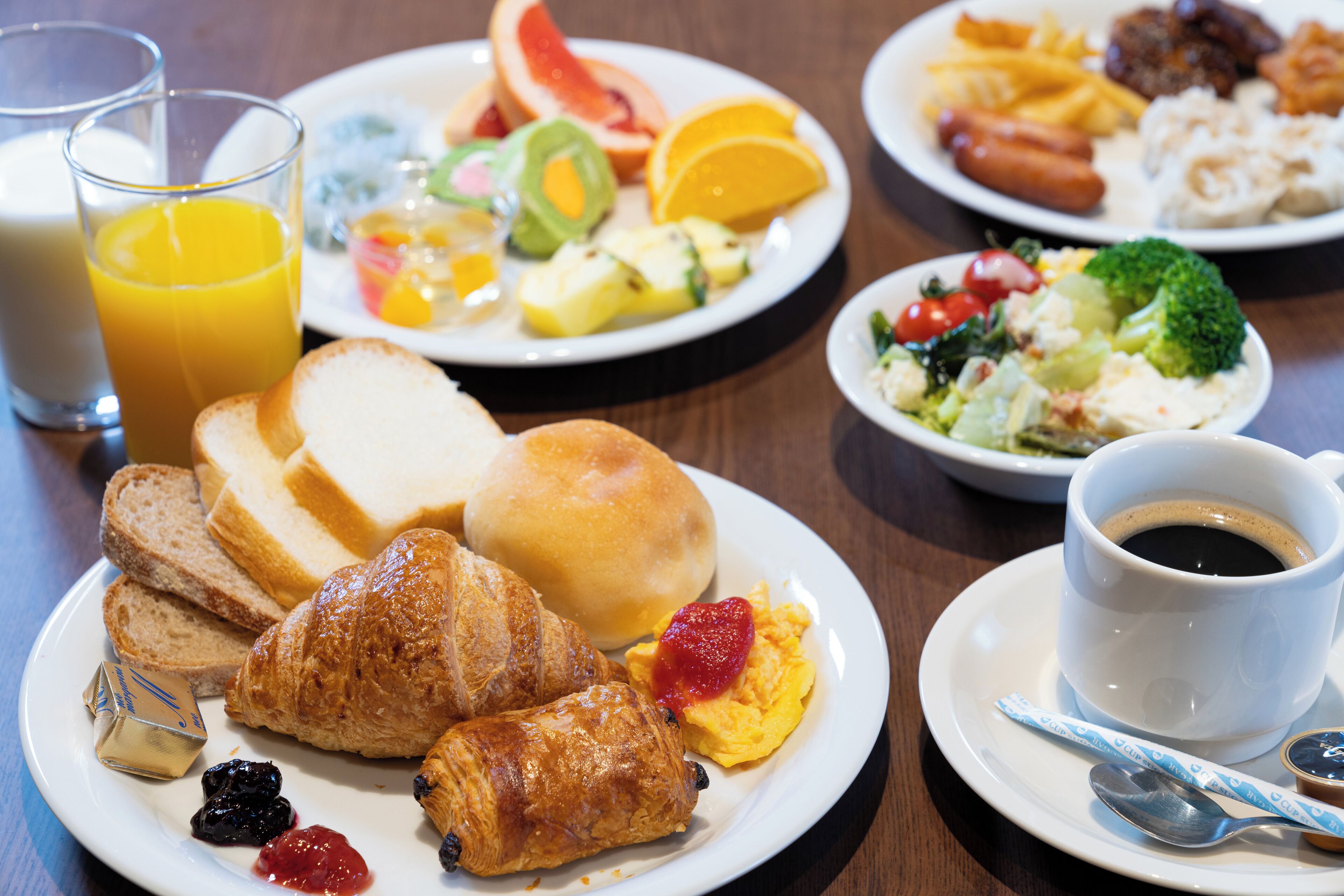 A breakfast setting with plates of food, a glass of orange juice, and a cup of coffee.