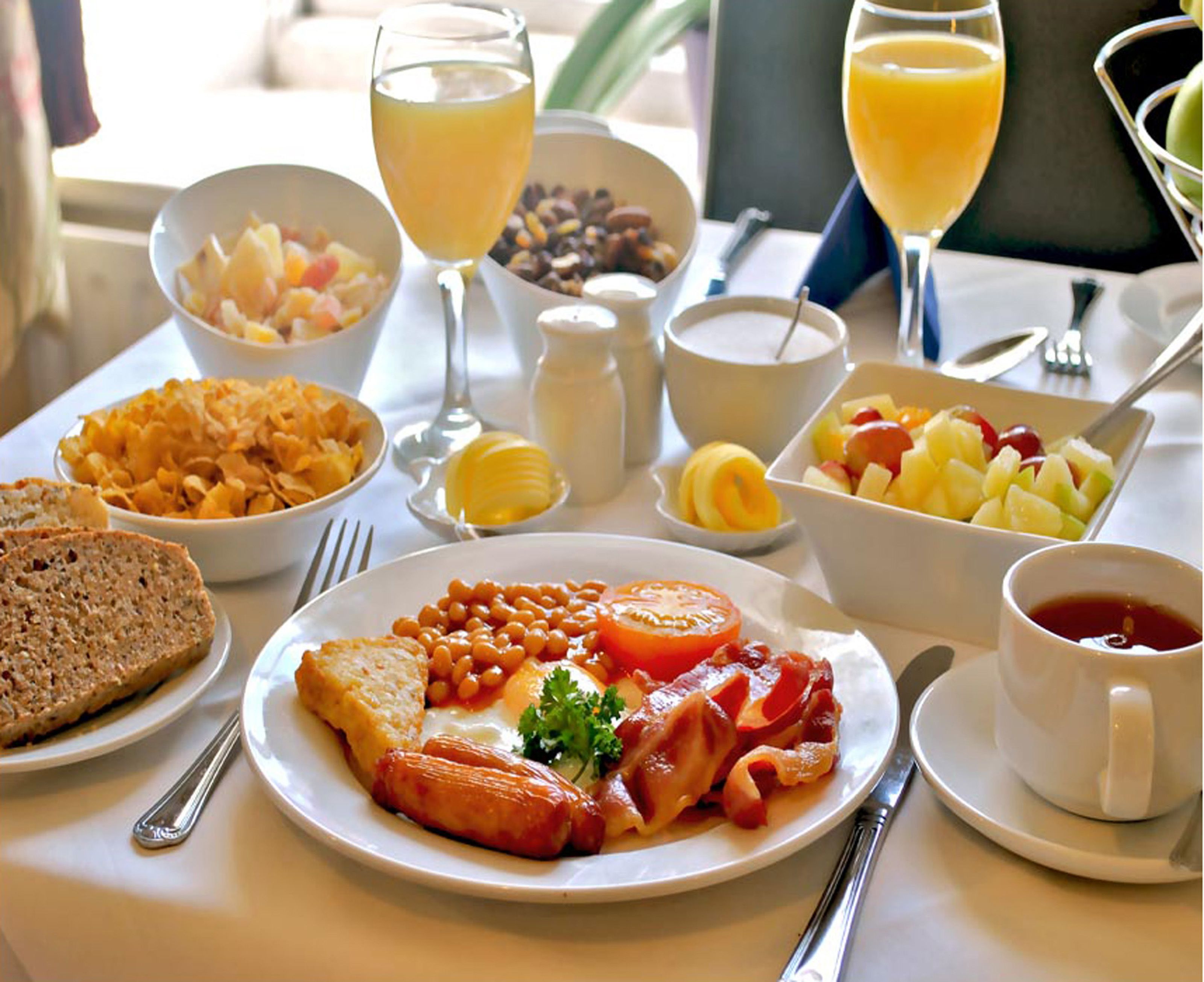 Et morgenbord med forskelligt mad, herunder ristet brød, bønner, tomater og æg.