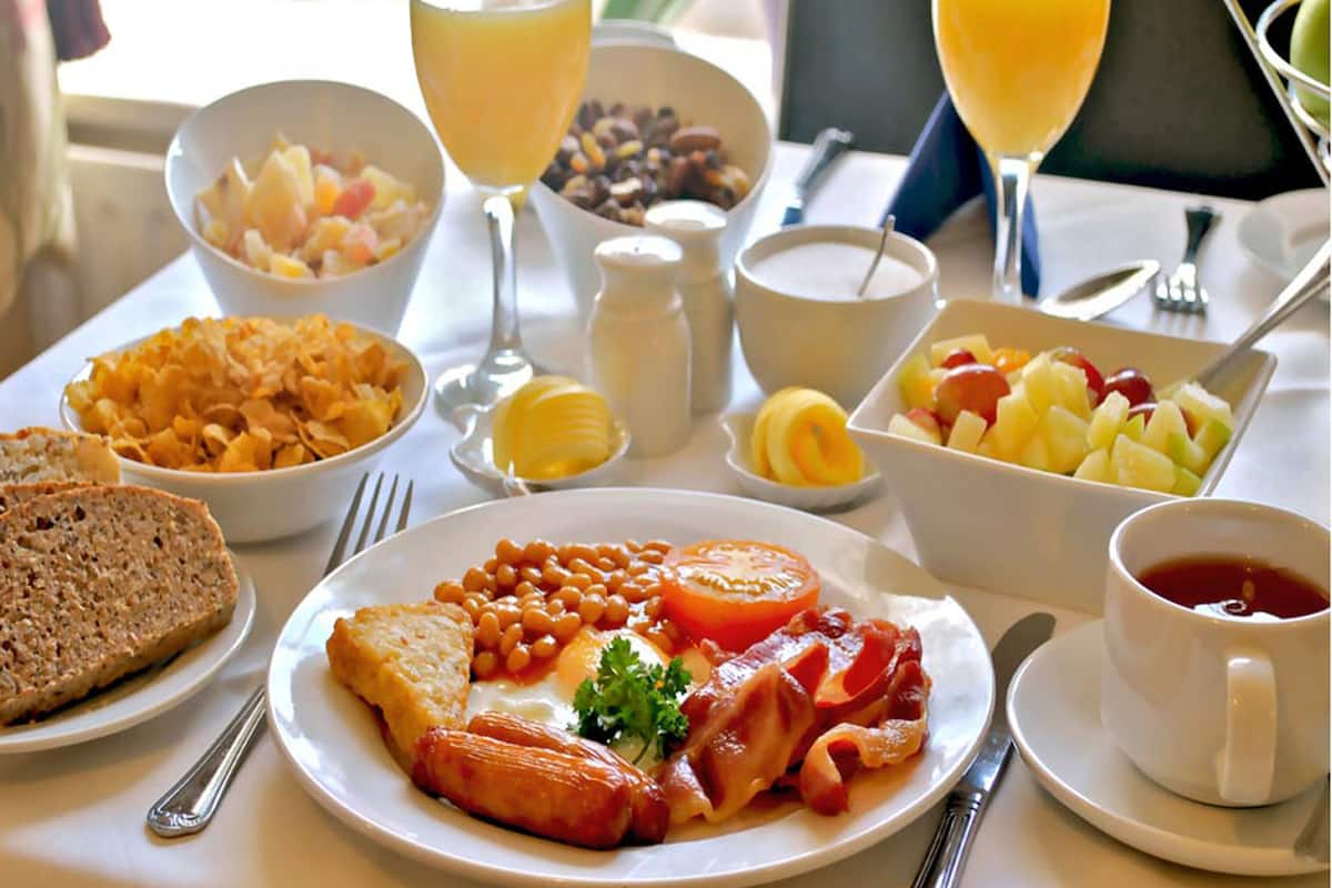 A breakfast table with various dishes including toast, beans, tomatoes, and eggs.