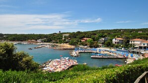 A coastal marina with boats docked, a pier with umbrellas, and buildings in the background. - Fattoria nel Parco (Rosignano Marittimo)