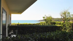 A view from a balcony overlooking a coastal landscape with a clear sky and distant hills. - Fattoria nel Parco (Rosignano Marittimo)