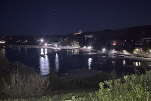 A nighttime view of a calm lake with illuminated docks and buildings in the background. - Fattoria nel Parco (Rosignano Marittimo)