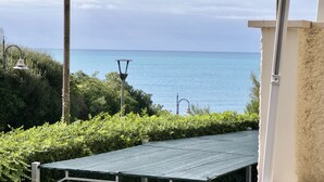 A view of the sea from a balcony with a metal table and a lamp post. - Fattoria nel Parco (Rosignano Marittimo)
