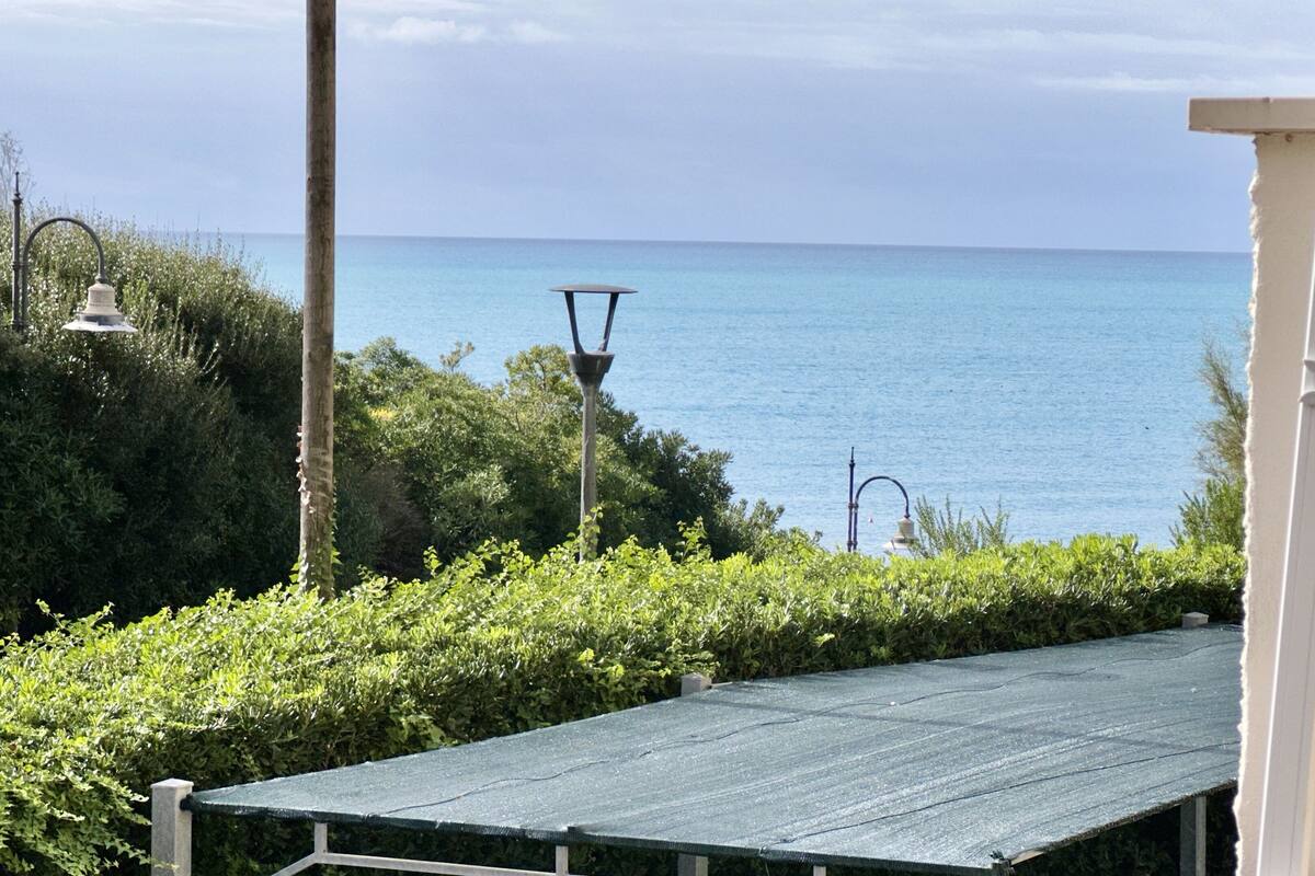 A view of the sea from a balcony with a metal table and a lamp post.