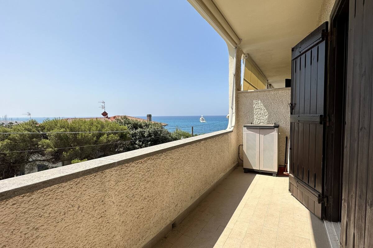 A balcony with a view of the sea, a wooden door, and a radiator.
