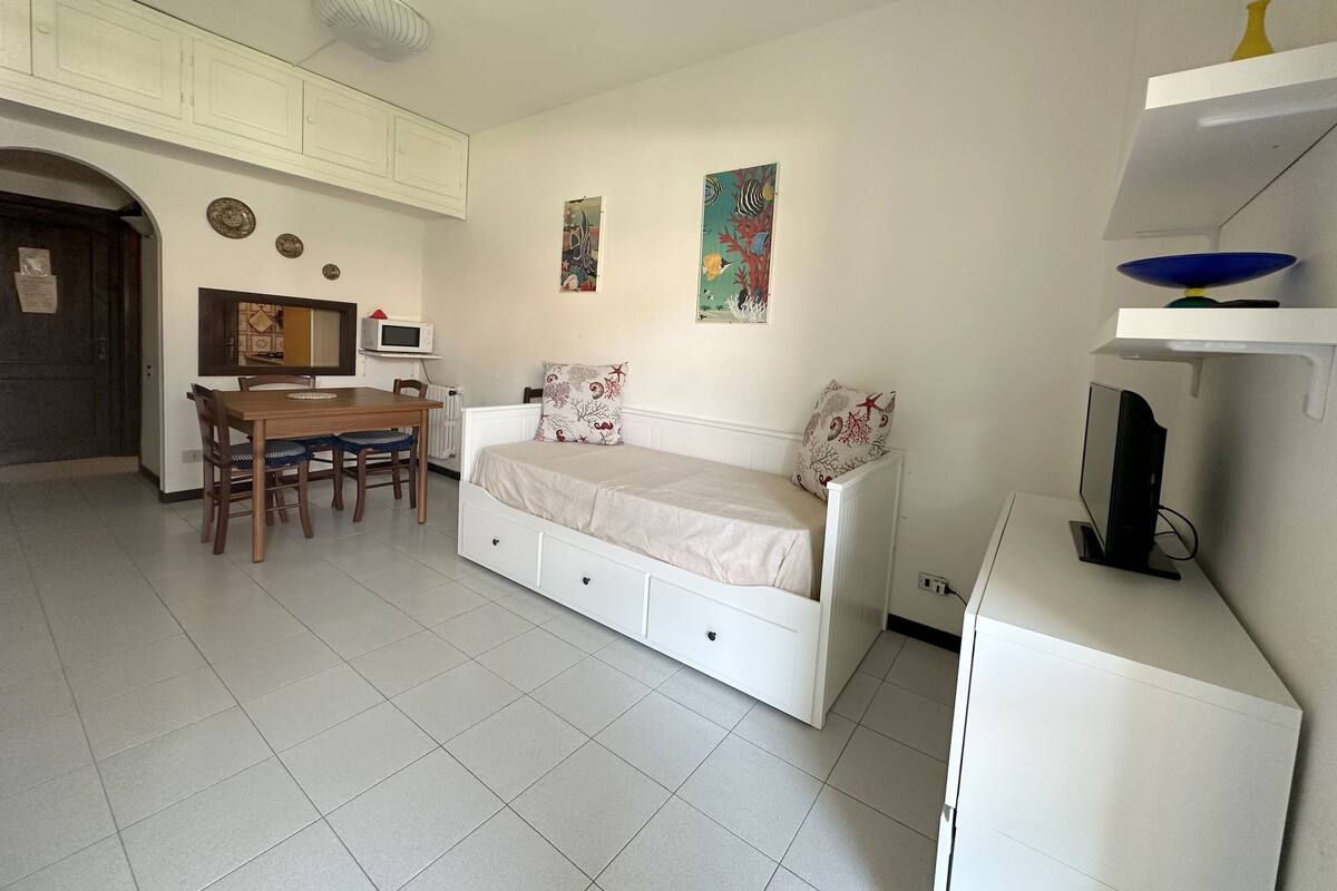 A compact living space with a kitchenette, a dining area, and a bed.