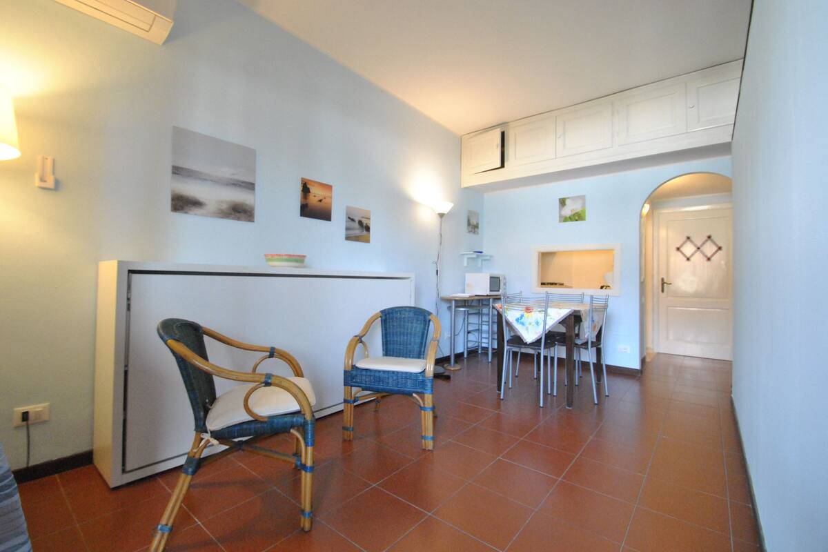 A dining area with a table and chairs, a refrigerator, and a microwave.