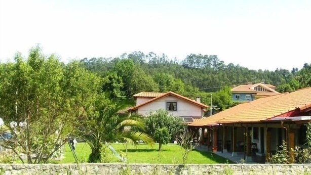 A residential area with houses, a stone wall, and greenery. - Picu Castiellu Aparthotel (Llanes)