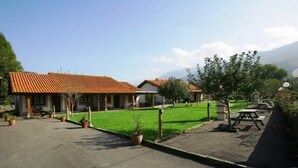 A residential area with a house featuring a tiled roof, a paved driveway, and a well-maintained lawn. - Picu Castiellu Aparthotel (Llanes)