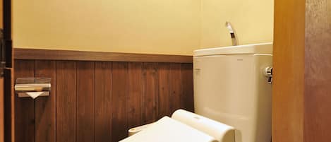 Un baño pequeño y funcional con suelo de madera, inodoro blanco y lavamanos empotrado en la pared.