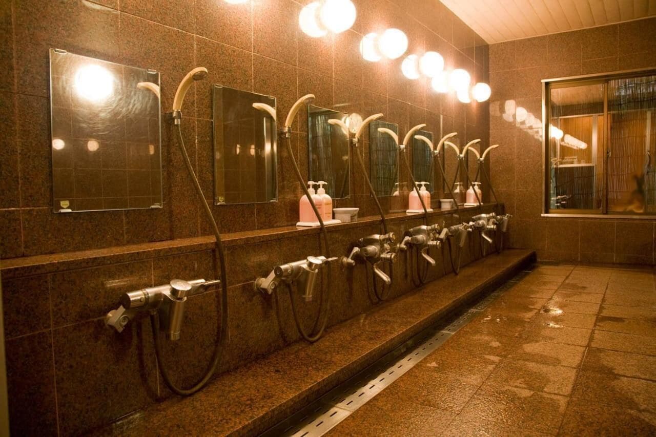 Sanitário público com várias pias e espelhos, equipado com torneiras e dispensadores de sabão.