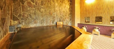Un sauna aux murs de pierre, avec un banc en bois et un sol carrelé.
