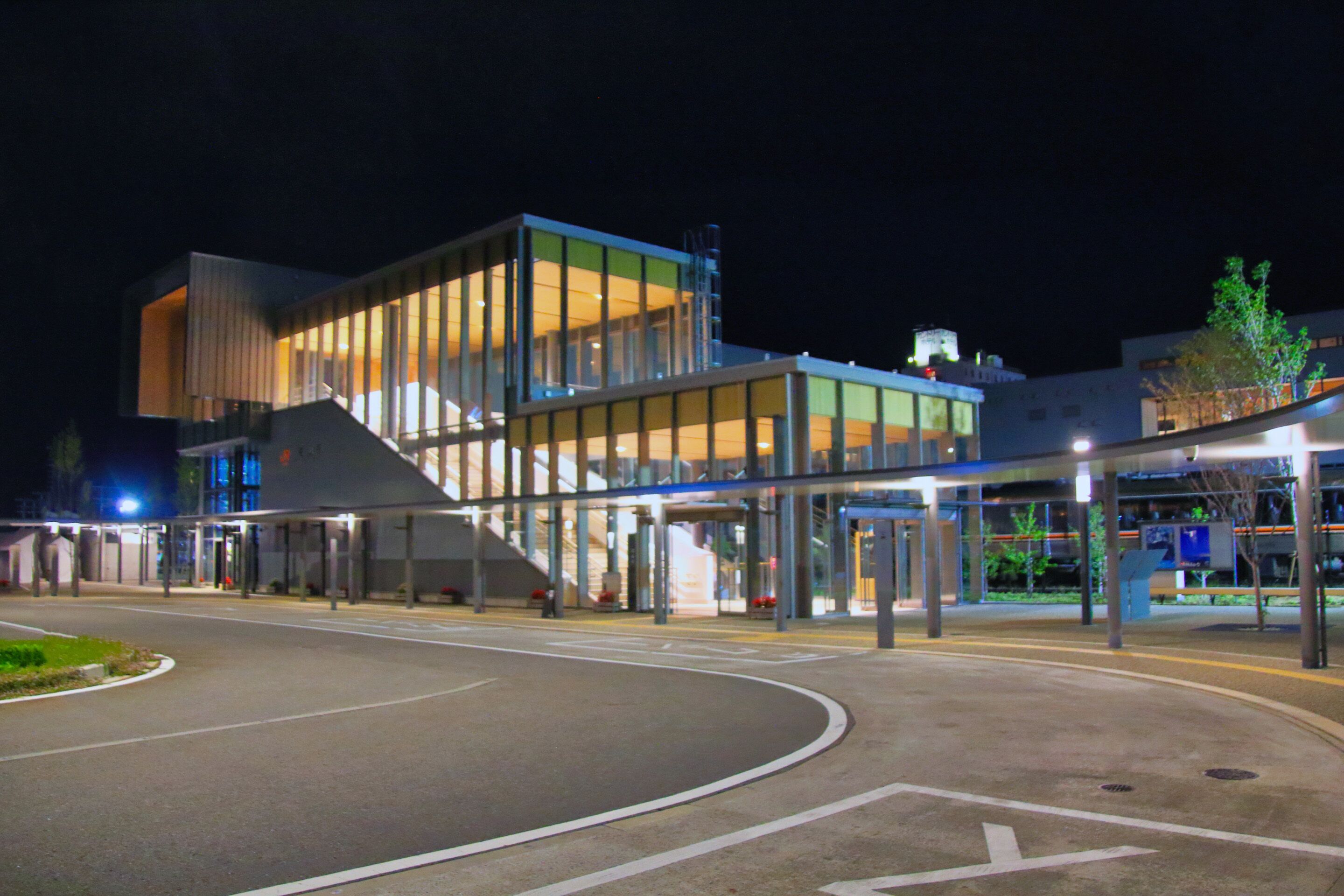 Un edificio moderno con fachada de vidrio y una rampa que conduce a la entrada.