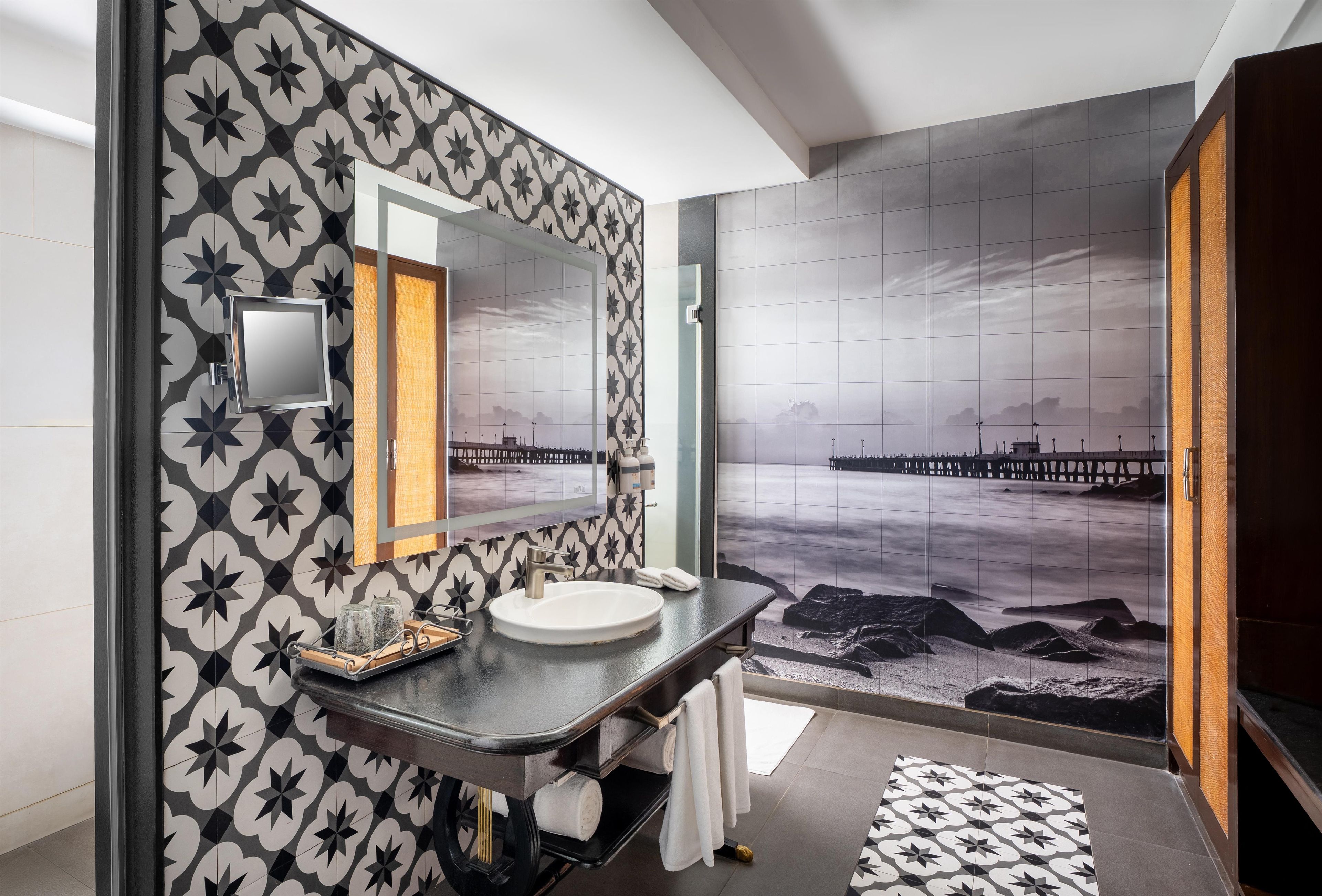 Un baño moderno con un espejo grande, un lavamanos y vistas a un muelle a través de un ventanal amplio.