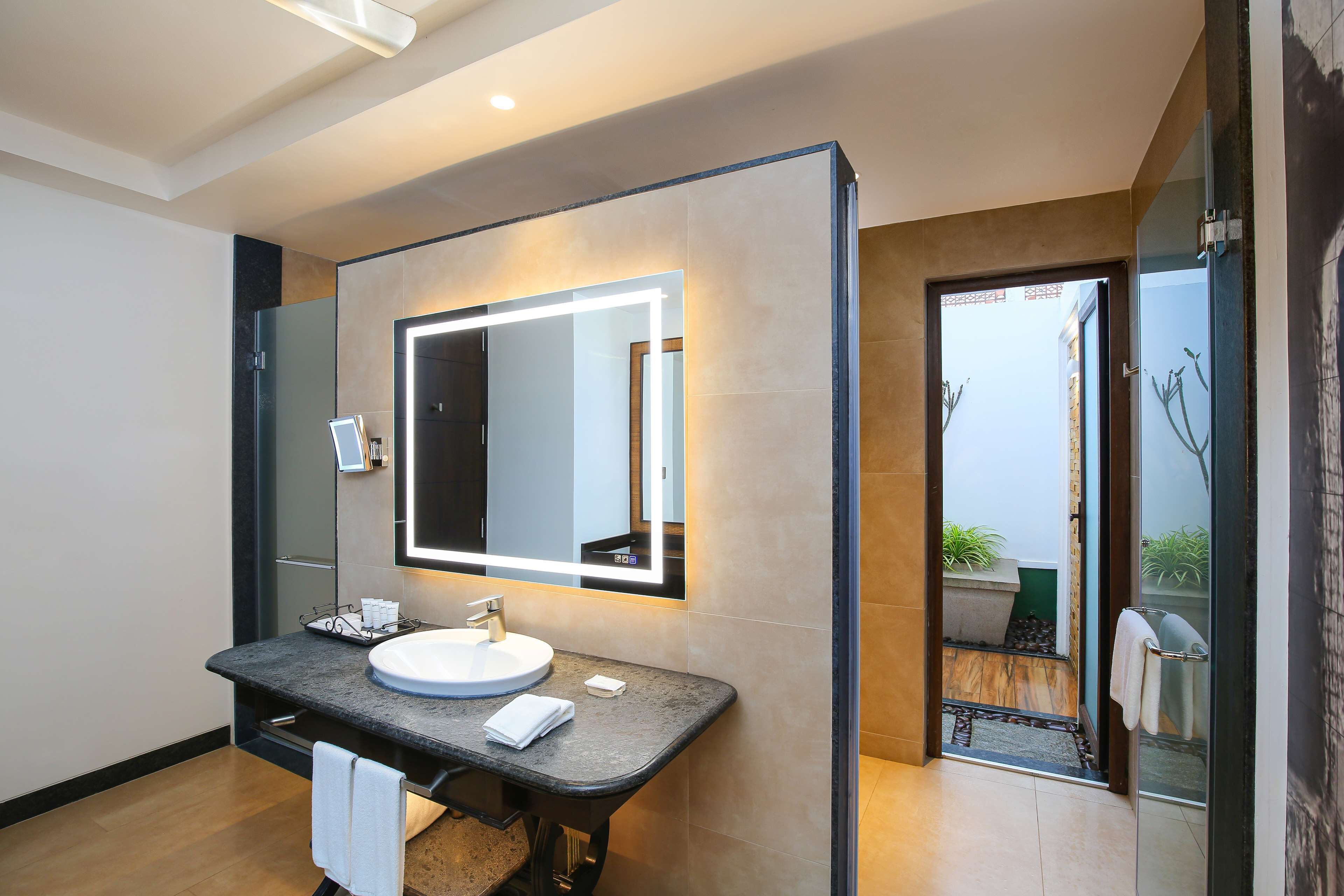 Un baño moderno con un espejo grande, un lavabo redondo y un perchero para toallas.