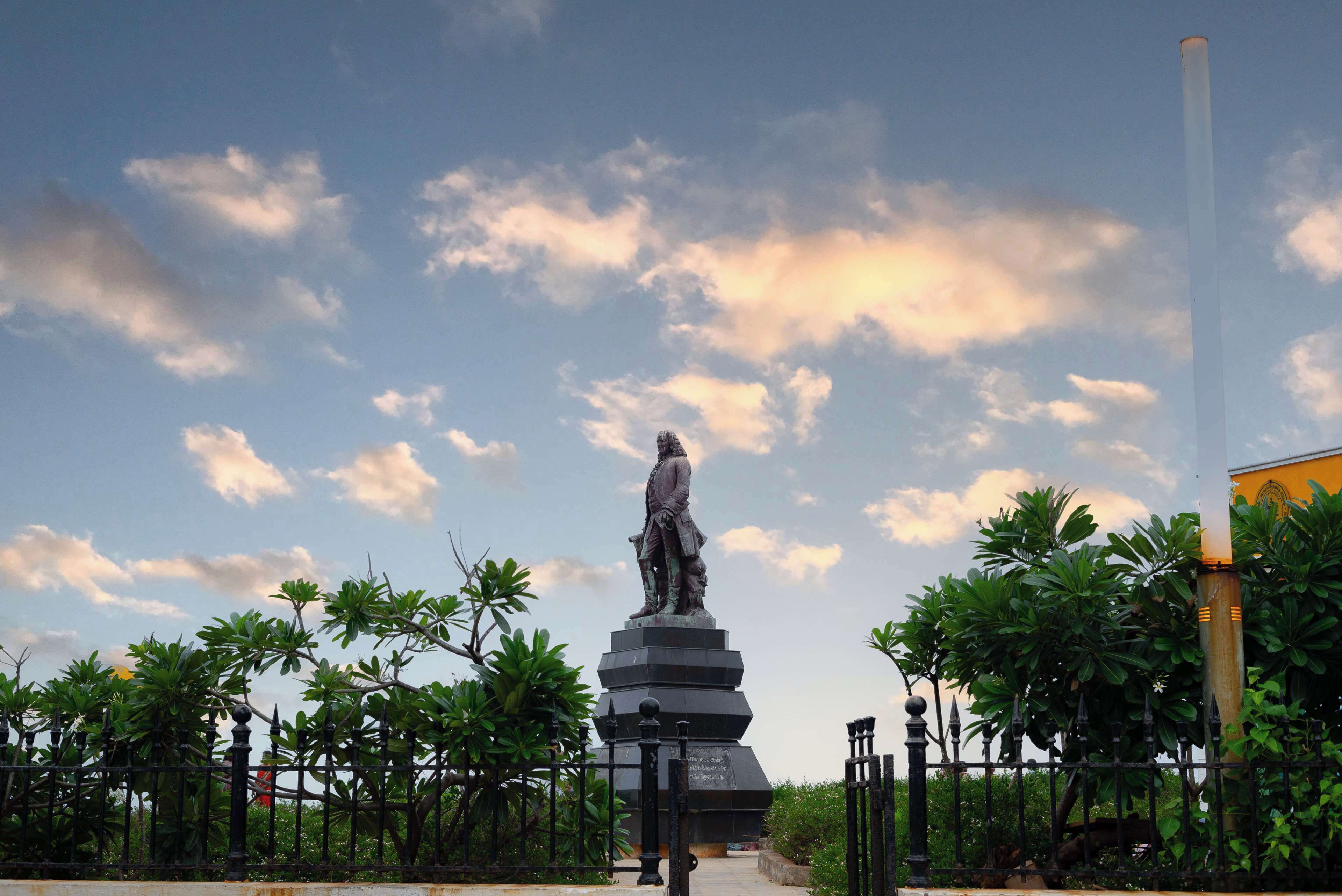 A statue in a park with a clear sky and trees.