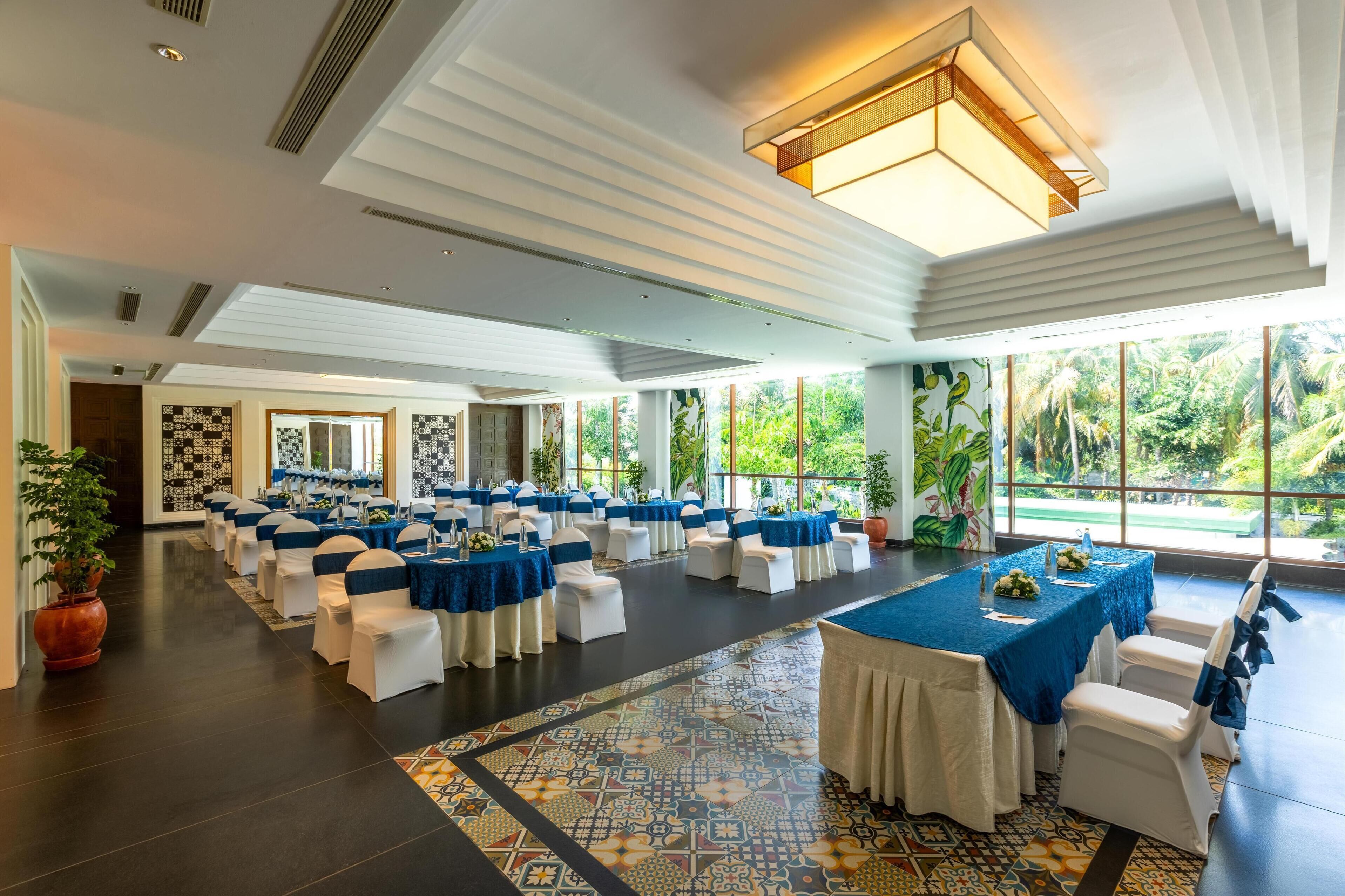 A spacious hall with rows of tables and chairs, large windows, and a patterned floor.