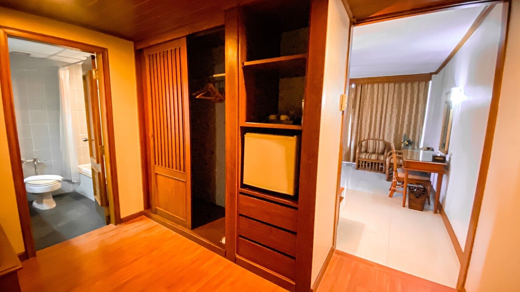 A room with a wooden wardrobe, a mirror, and a small table with chairs.