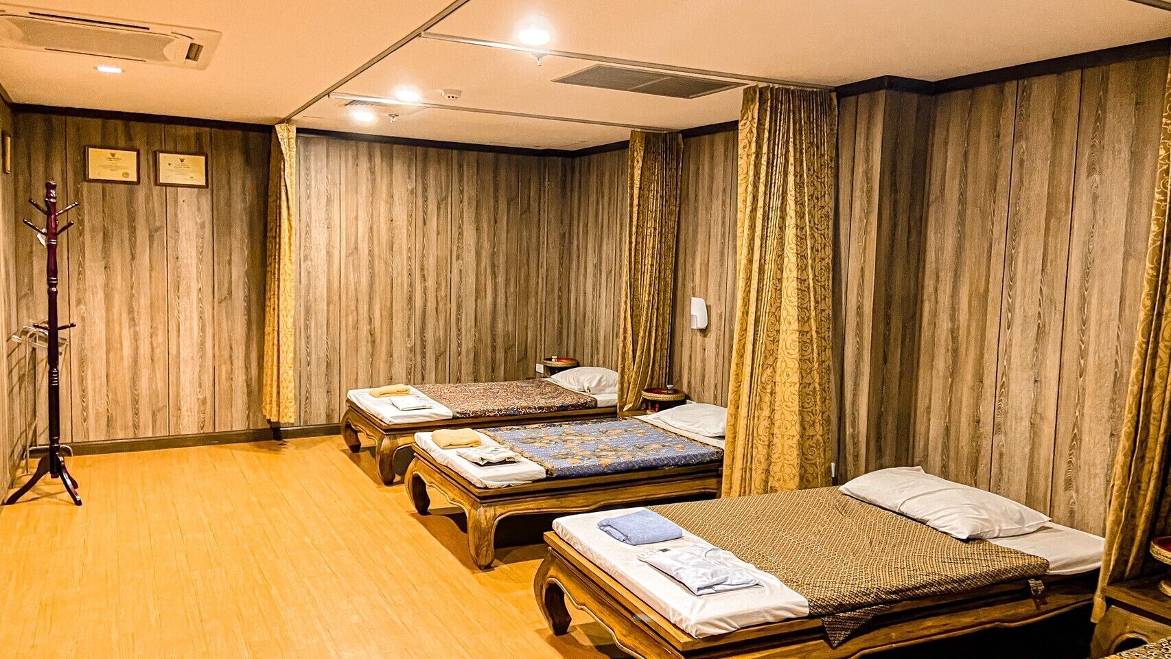 A hotel room with three wooden beds, a wooden floor, and a wooden wall paneling.