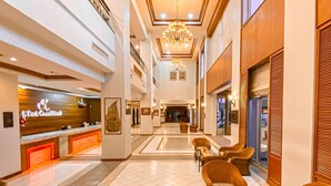A hotel lobby with a reception desk, seating area, chandeliers, and framed artwork on the walls. - K Park Grand Hotel (Surat Thani)