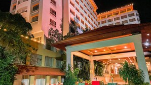 A multi-story hotel with a covered outdoor area featuring plants and a staircase leading to the entrance. - K Park Grand Hotel (Surat Thani)