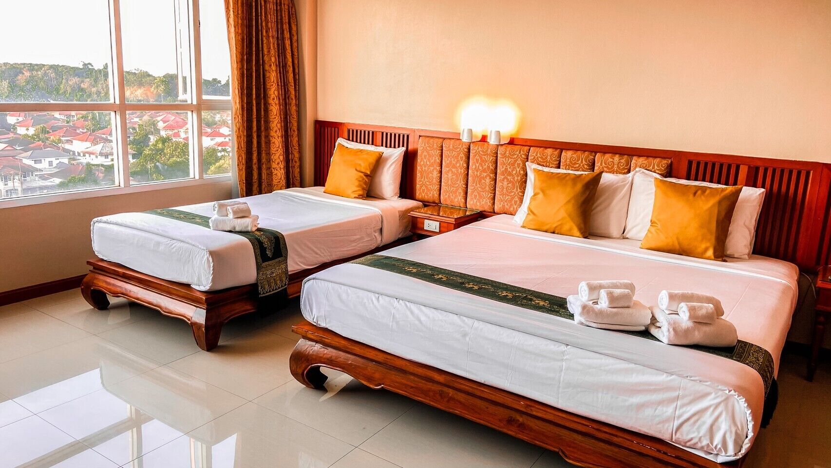 A hotel room with two beds, a large window, and a view of the city.