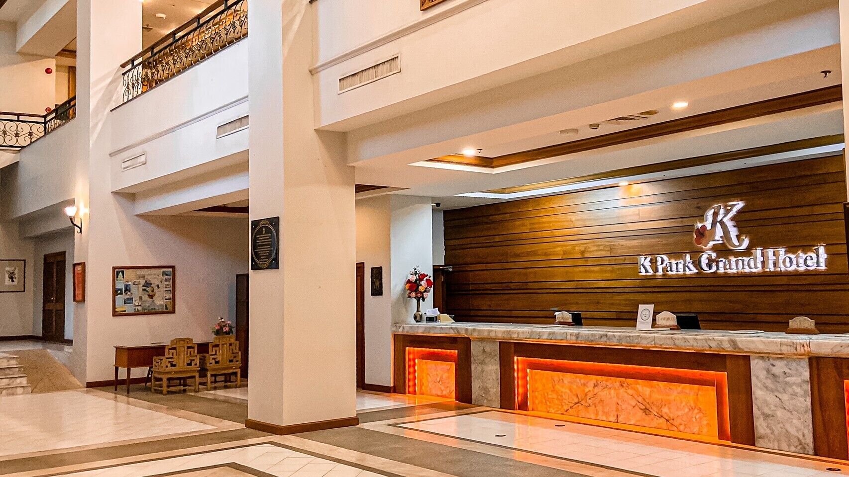 A reception area with a marble counter, a wooden reception desk, and a staircase leading to an upper floor.