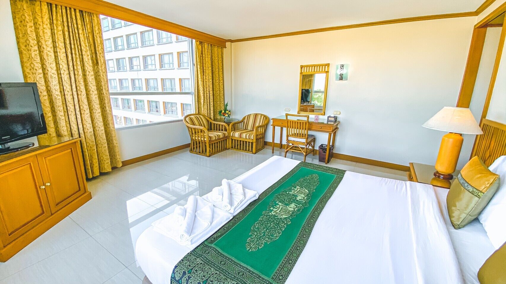 A hotel room with a bed, a desk, a chair, a television, and a window with curtains.